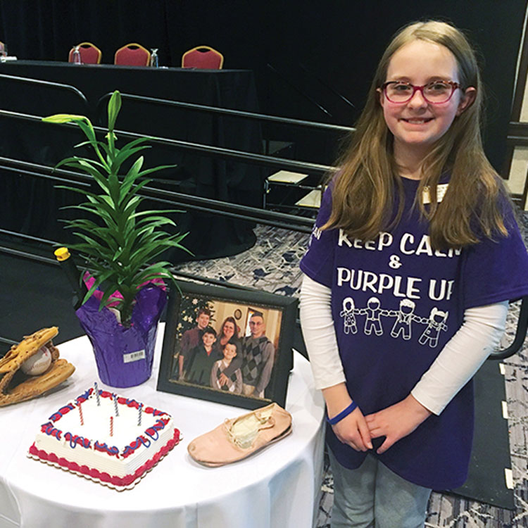 An ALA Junior member stands next to a Military Child’s Table Setting. You can honor our military children on April 15 with the designated holiday: Purple Up! Day.